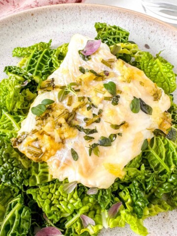 honey ginger baked cod on a bed of cabbage on a plate.